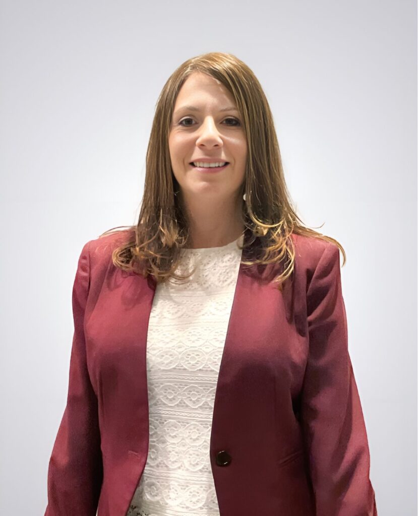 Professional headshot of a red haired woman smiling in a red blazer and white shirt in front of a white background - Alison Maybruck