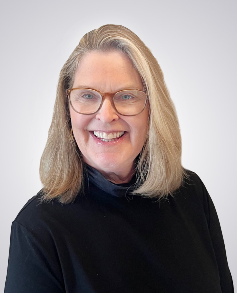 professional headshot of blonde woman with glasses smiling wearing a black sweater on a white background